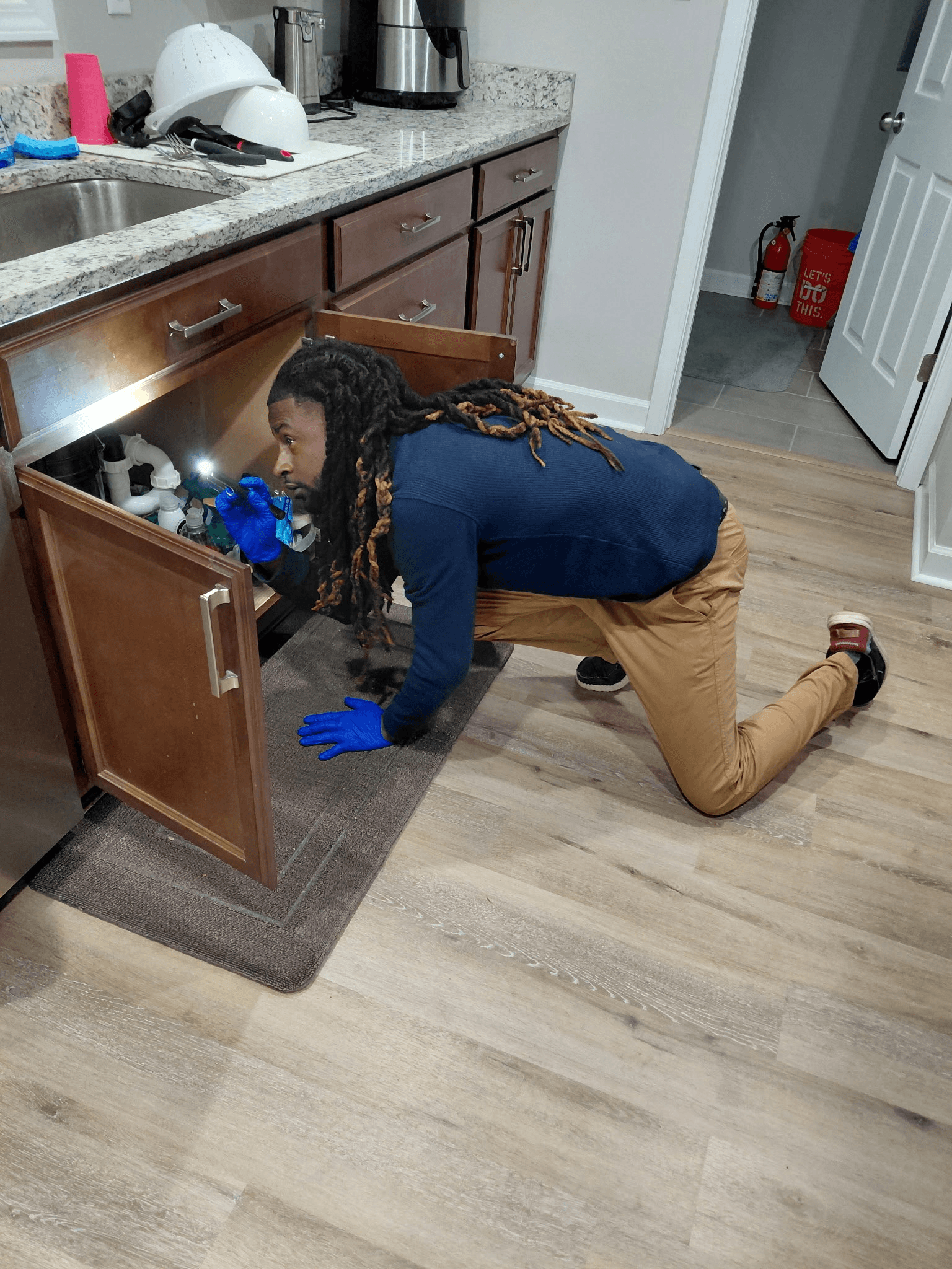 Prince inspecting under a Salisbury kitchen sink — inspection-first pest control